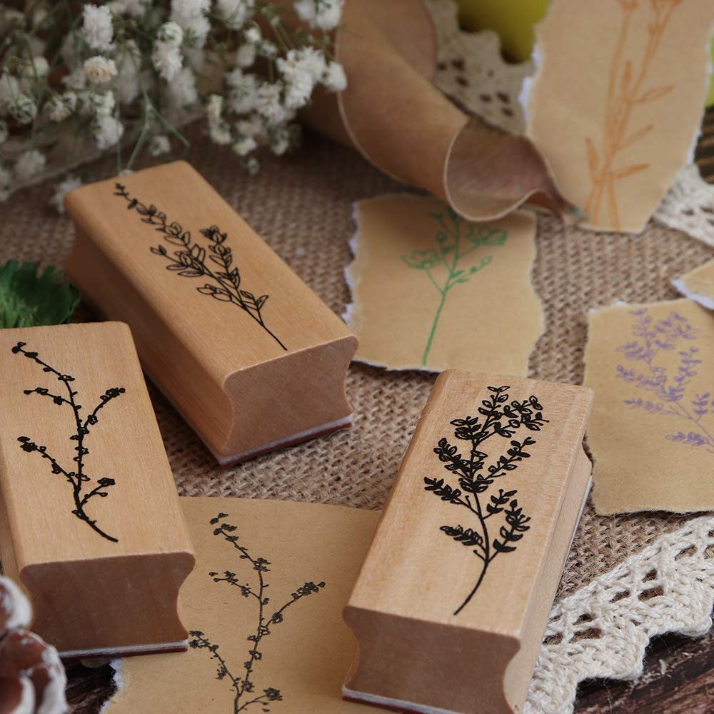 Three wooden rubber stamps with floral and plant designs, surrounded by stamped paper samples.
