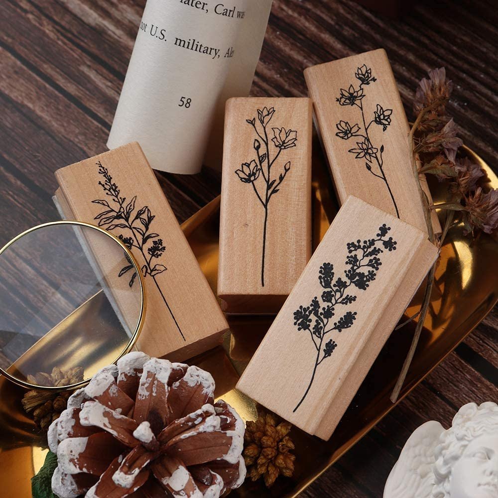 Four wood mounted rubber stamps with floral designs, arranged on a golden tray with decorative elements.