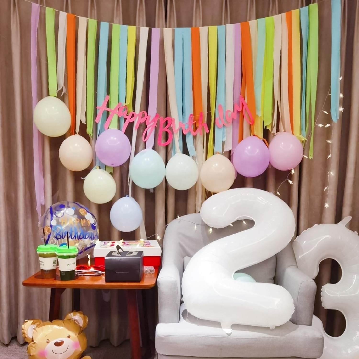 Birthday party scene with pastel crepe paper streamers, balloons, and large number balloons.
