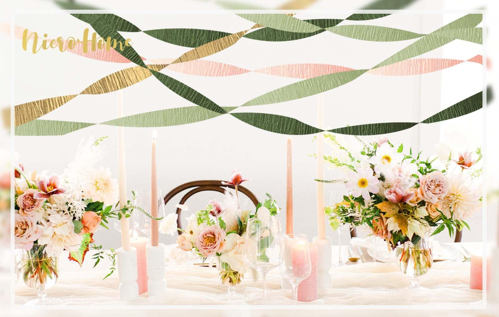 Table setting with floral arrangements and candles, decorated with green, pink, and gold streamers overhead.