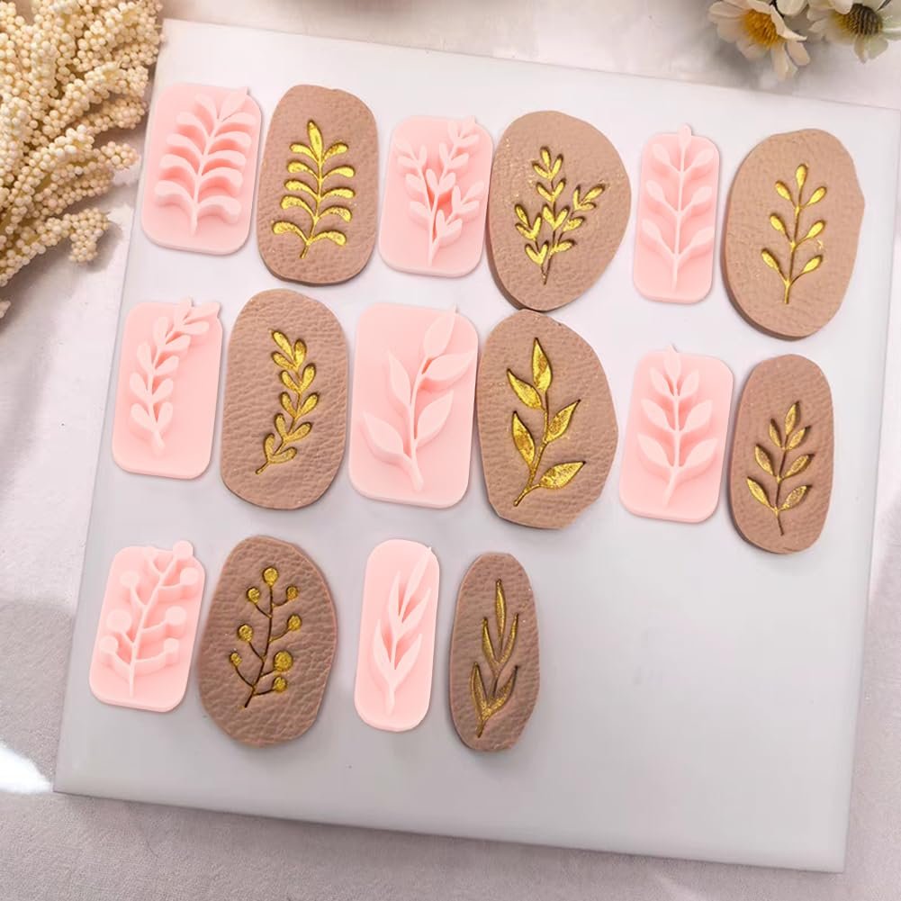 Set of 12 botanical polymer clay stamps and cutters with leaf and branch designs in pink and tan with gold accents, arranged on a white surface.