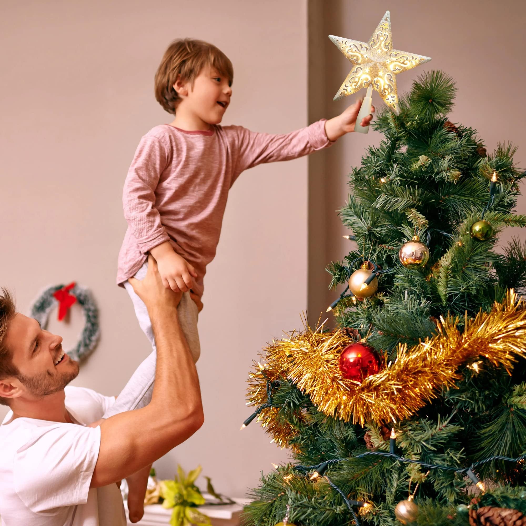Father holding son to place star tree topper on Christmas tree