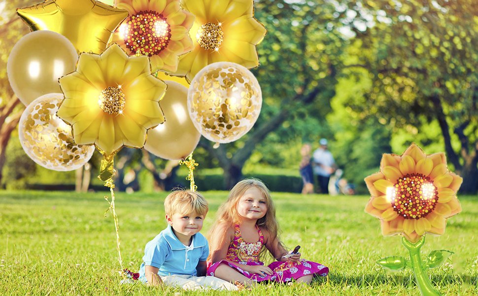 Two children sitting in grass with a bouquet of sunflower and star balloons