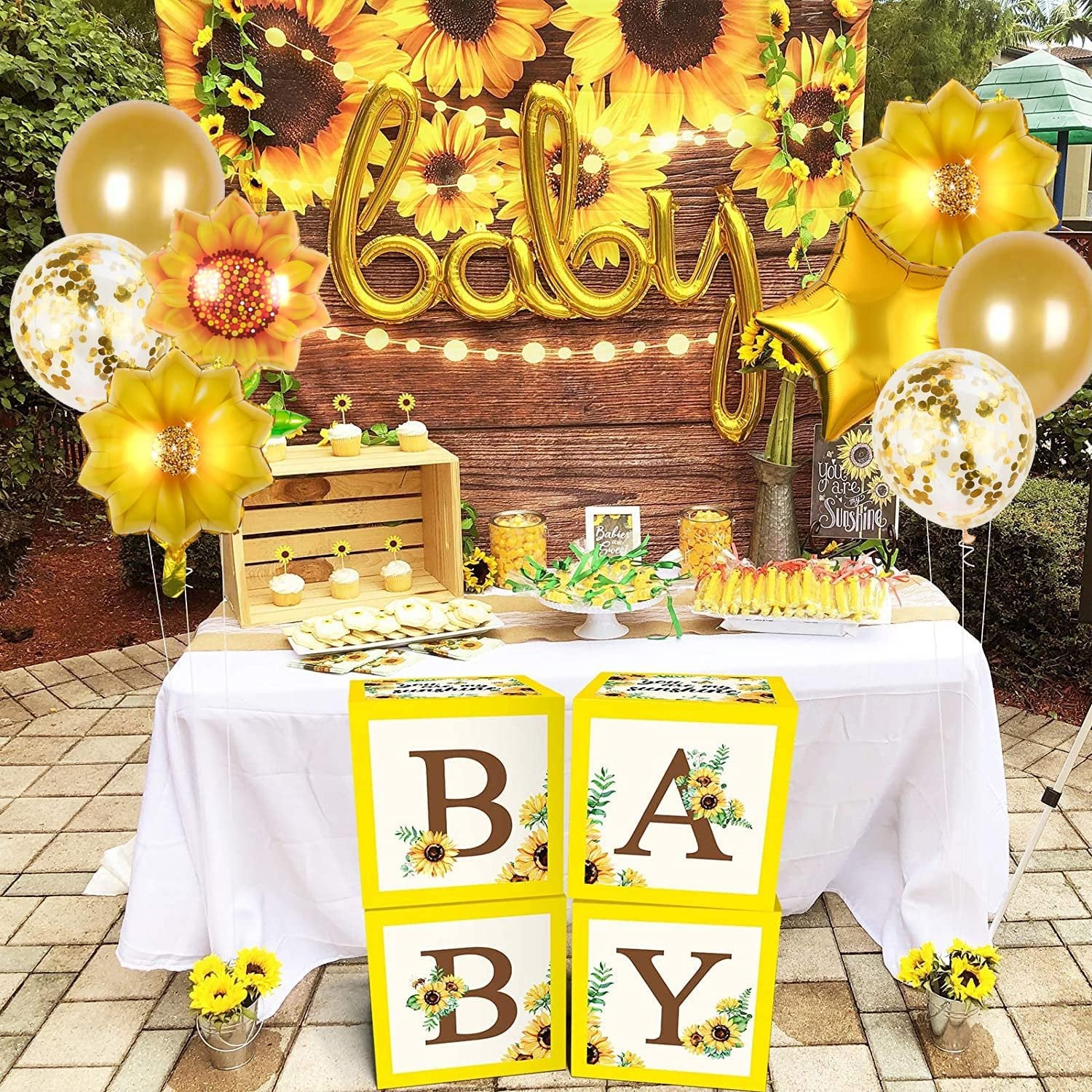 Party setup with 'BABY' balloons, sunflower balloons, star balloons, and confetti balloons, plus decorated blocks spelling 'BABY'.