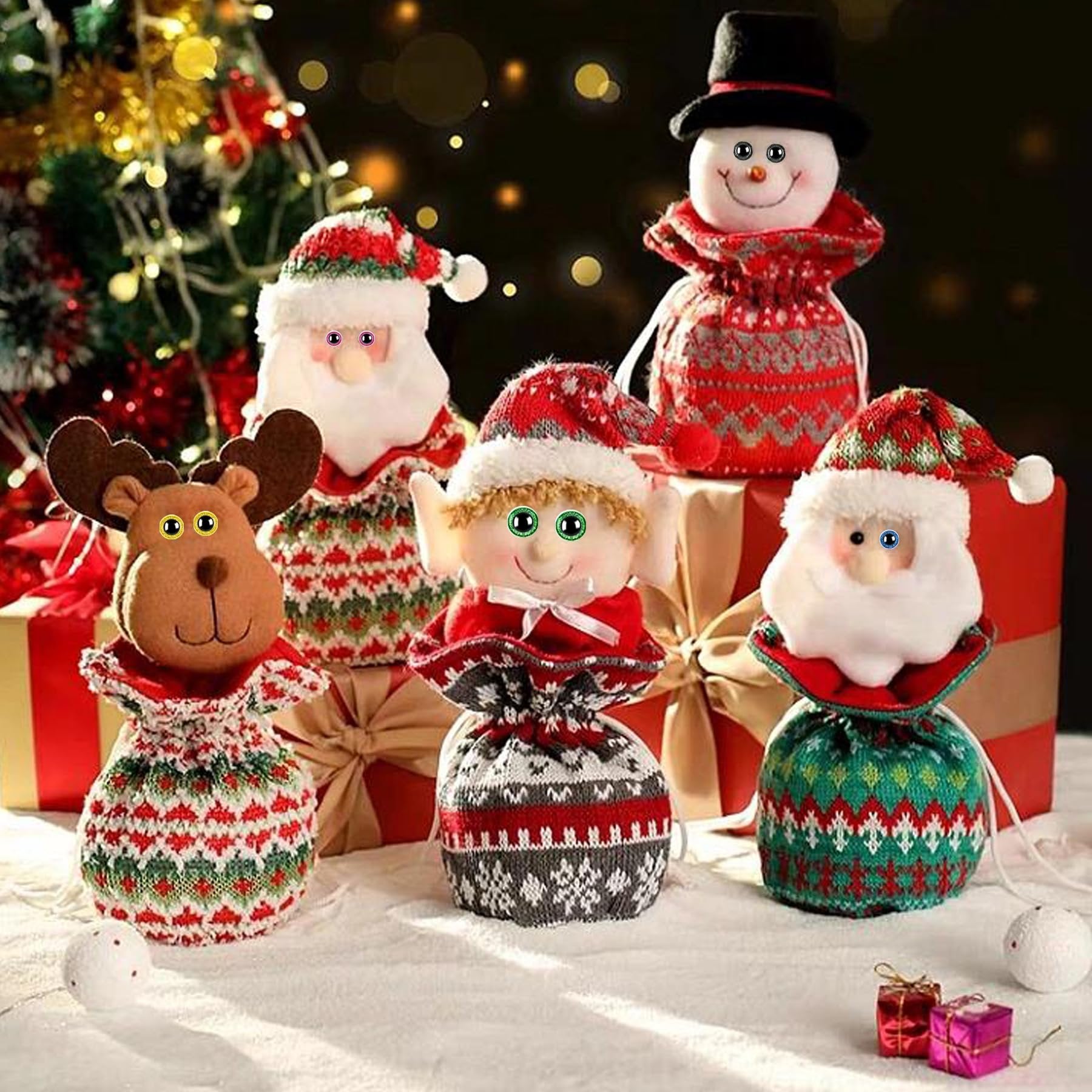 Christmas character gift bags including Santa, reindeer, elf, and snowman, arranged on a snowy surface with gift boxes and a Christmas tree in the background.