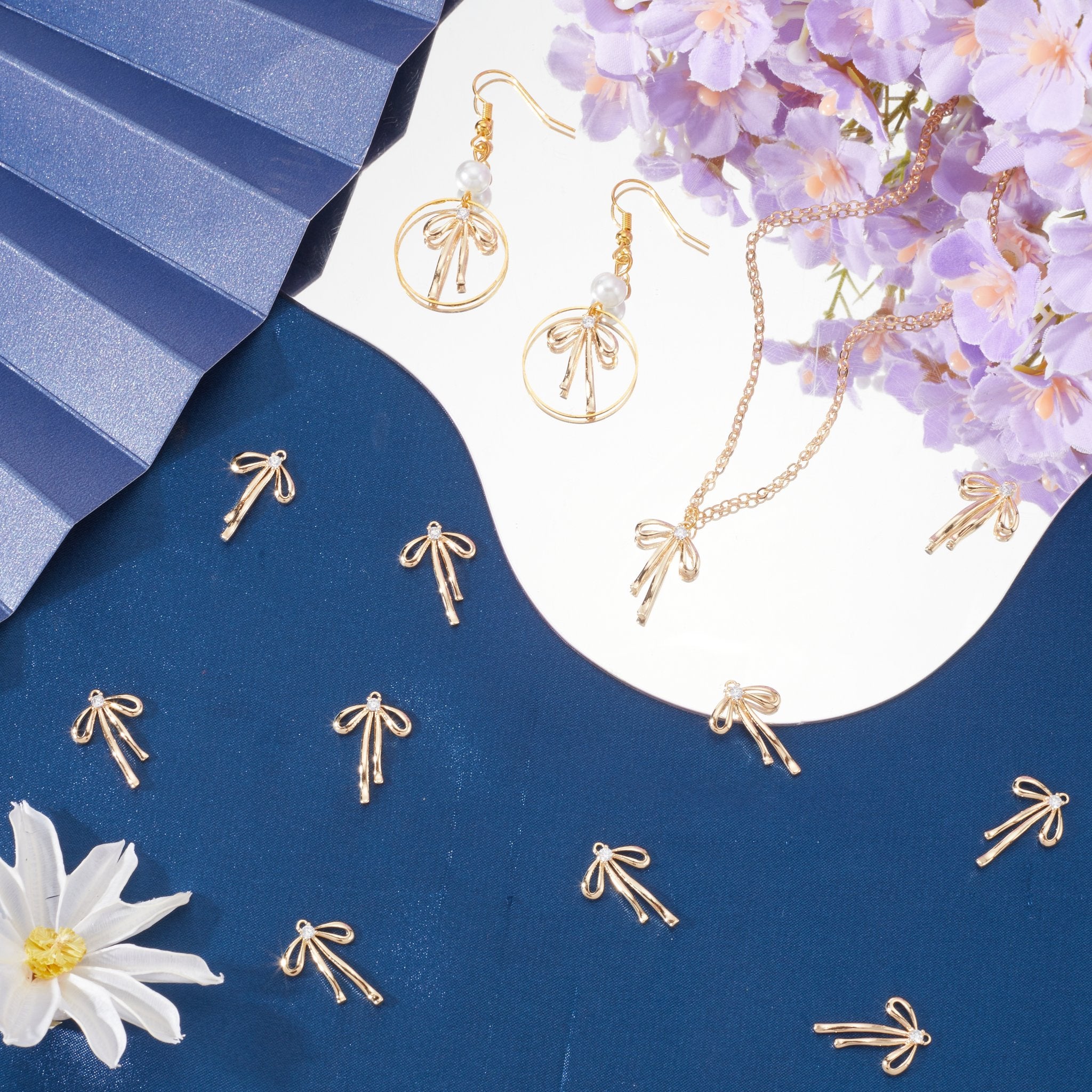 Gold bow charms, earrings, and necklace with pearl and diamond accents on a blue and white background with purple flowers