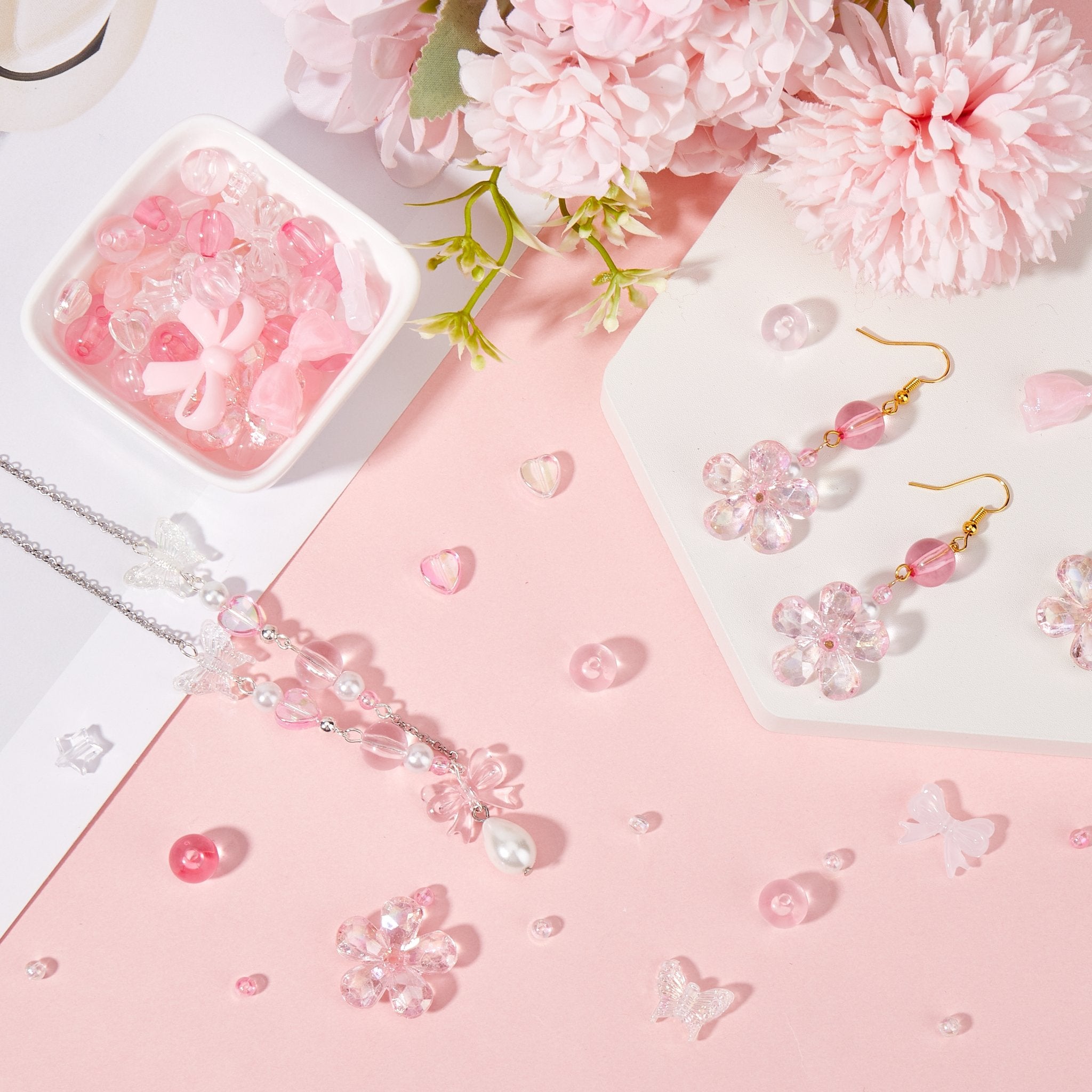 Pink enamel bow charms and flower charms with beads arranged for jewelry making