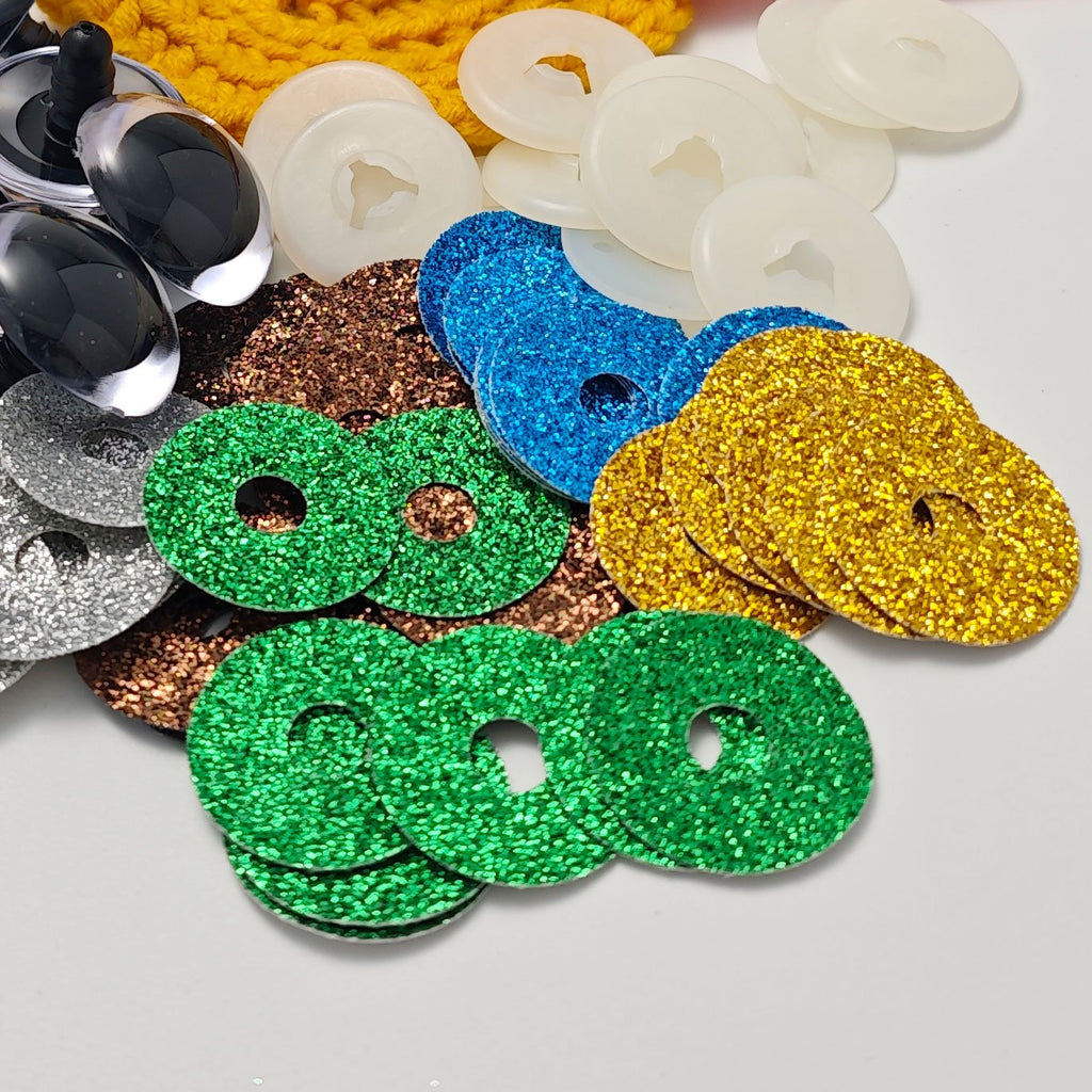 Assorted glitter safety eyes and plastic washers for amigurumi crafts on a white background.