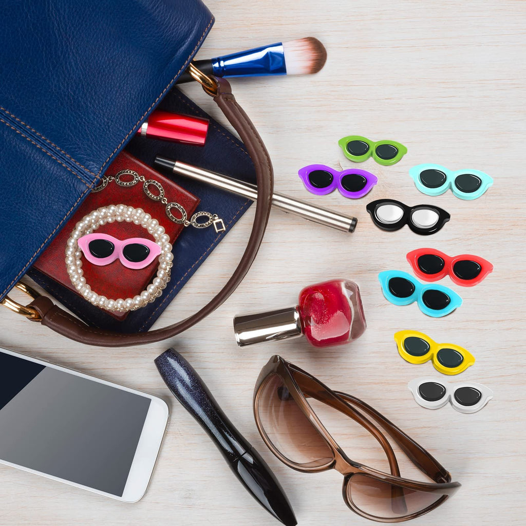 Flat lay of various makeup items and colorful resin sunglasses charms scattered on a wooden surface.