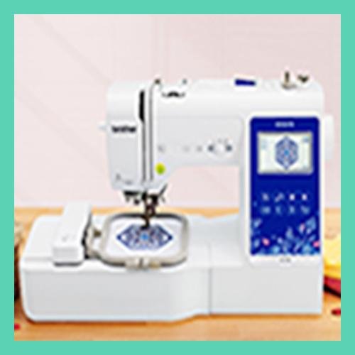 White embroidery sewing machine with blue digital display showing a geometric pattern, set on a wooden surface.