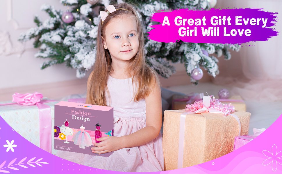Young girl holding a fashion design sewing kit box in front of a Christmas tree and gifts