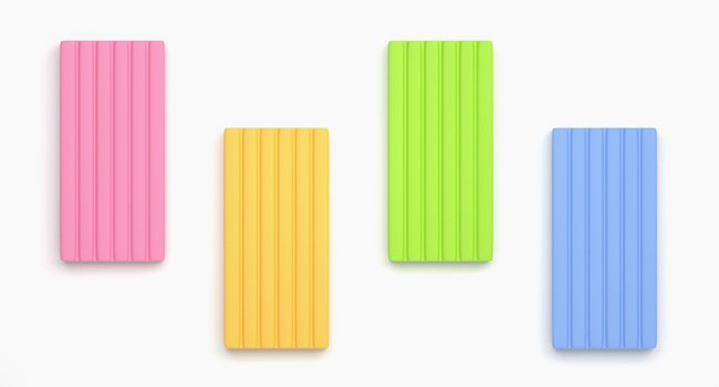 Four rectangular blocks of polymer clay in pink, yellow, green, and blue, arranged on a white background.