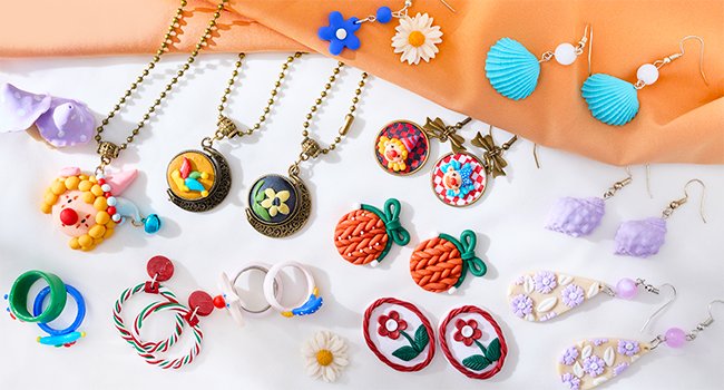 Assortment of colorful polymer clay jewelry including necklaces, earrings, and rings, laid out on a white and orange surface.