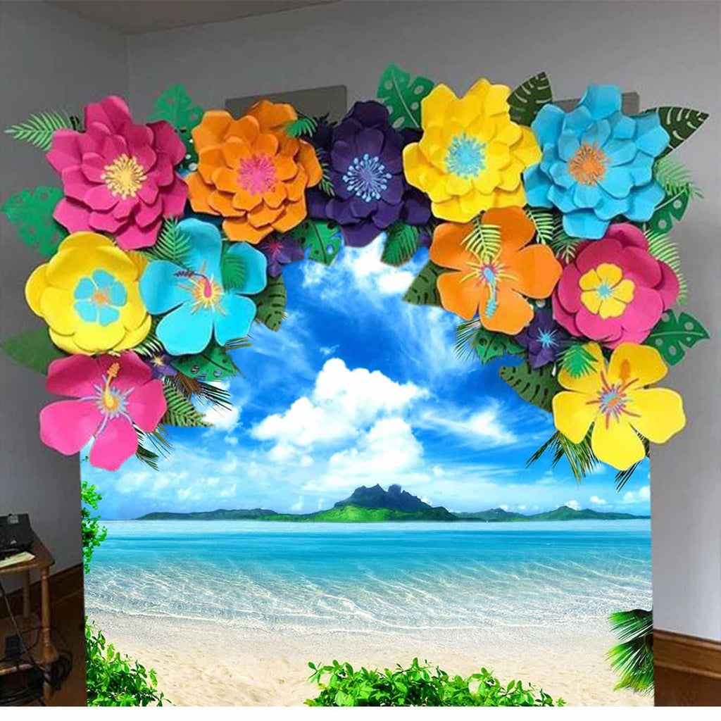 Tropical beach backdrop with colorful paper flowers framing a scenic ocean view and island.