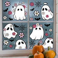 Halloween window clings featuring cute ghosts, bats, flowers, and spiderwebs applied to a window with pumpkins below.