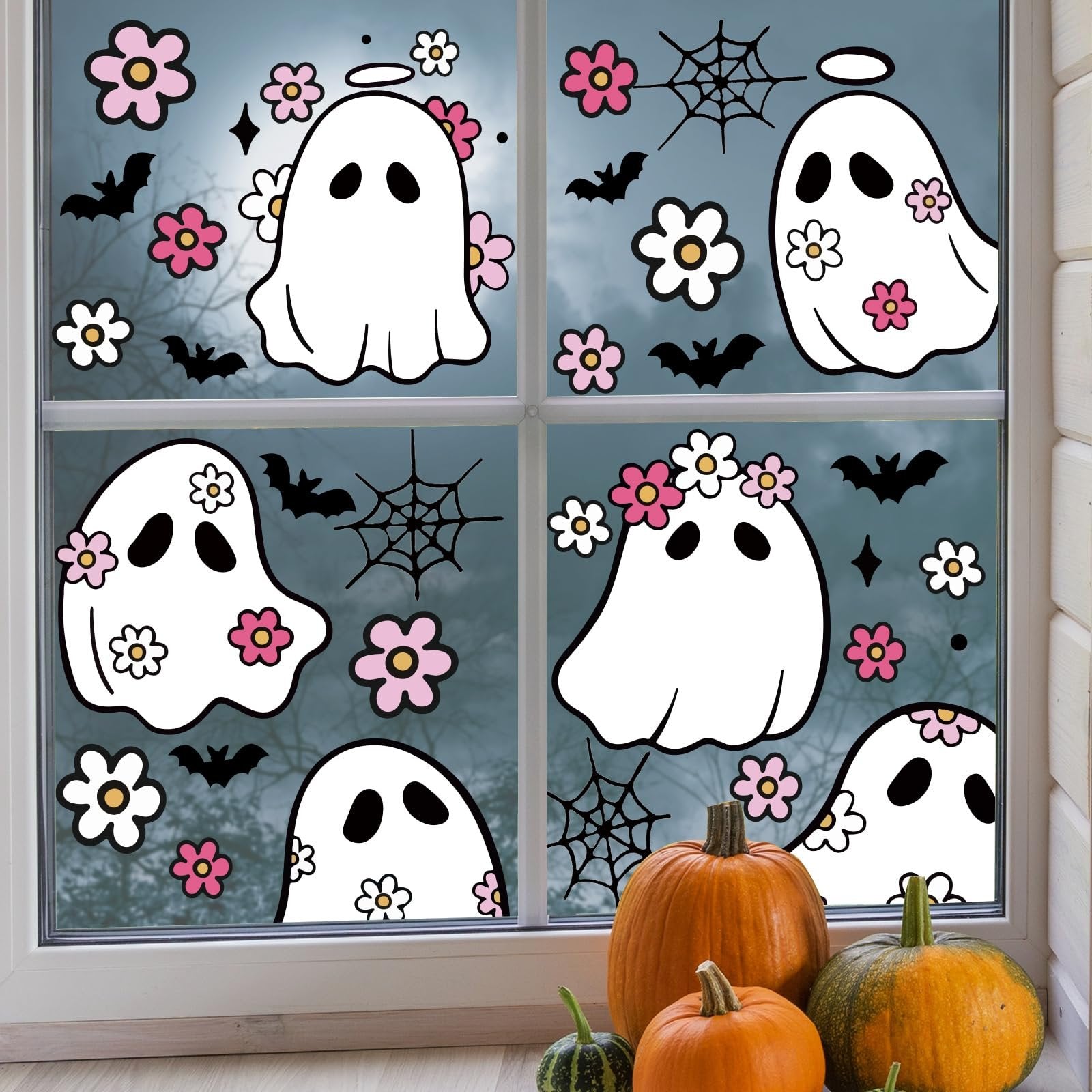 Halloween window clings featuring cute ghosts, bats, flowers, and spiderwebs applied to a window with pumpkins below.