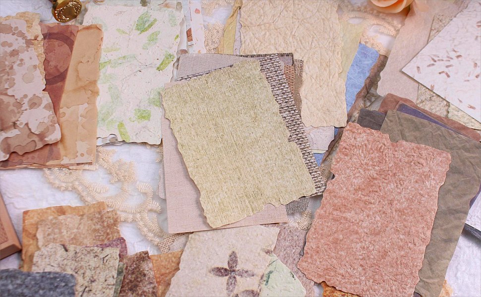 Assortment of textured and deckled-edge scrapbook papers in various vintage colors and patterns, flat lay.