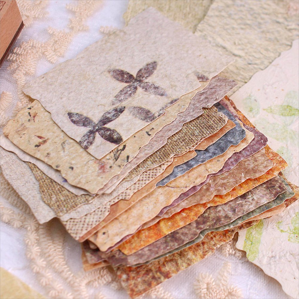 Stack of textured vintage scrapbook paper with deckled edges and floral patterns