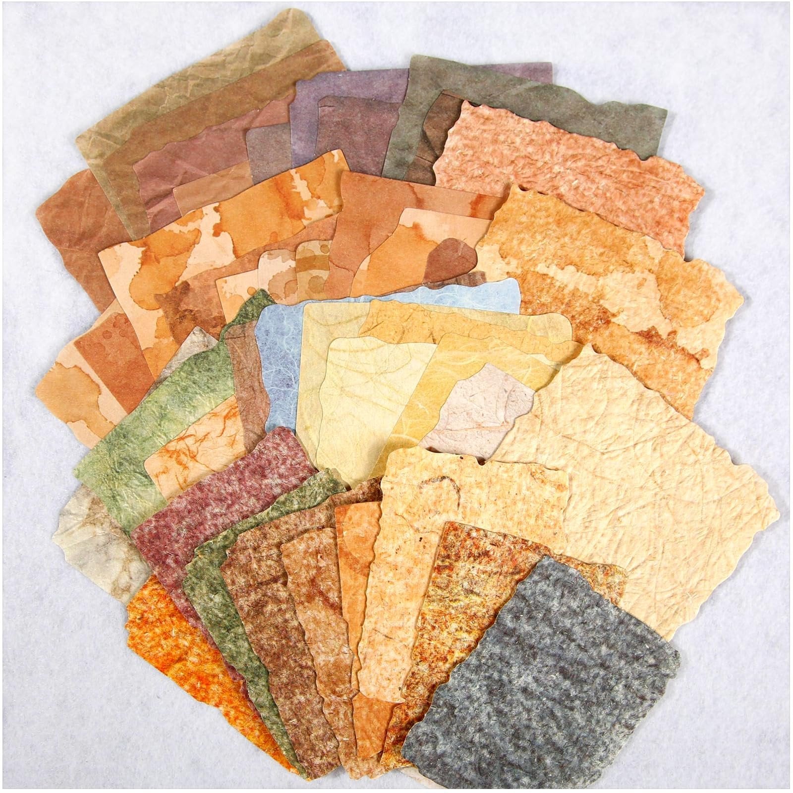 Assortment of textured, deckled-edge scrapbook papers in various vintage earth tones, fanned out on a white background.