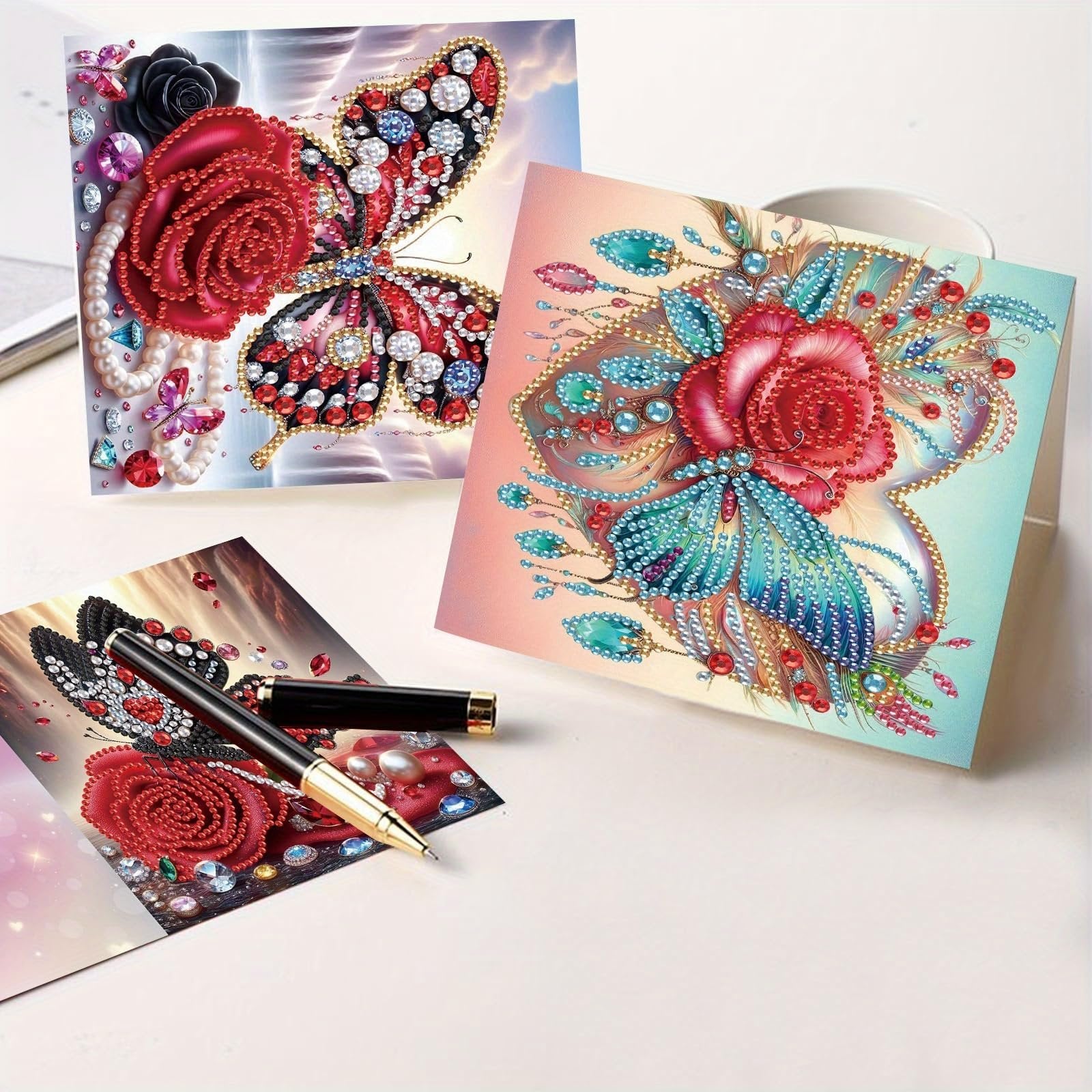 Diamond art greeting cards featuring roses and butterflies, with a pen on one card.