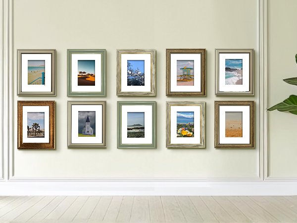 Gallery wall display of ten rustic farmhouse picture frames with landscape photos, arranged on a light wall.