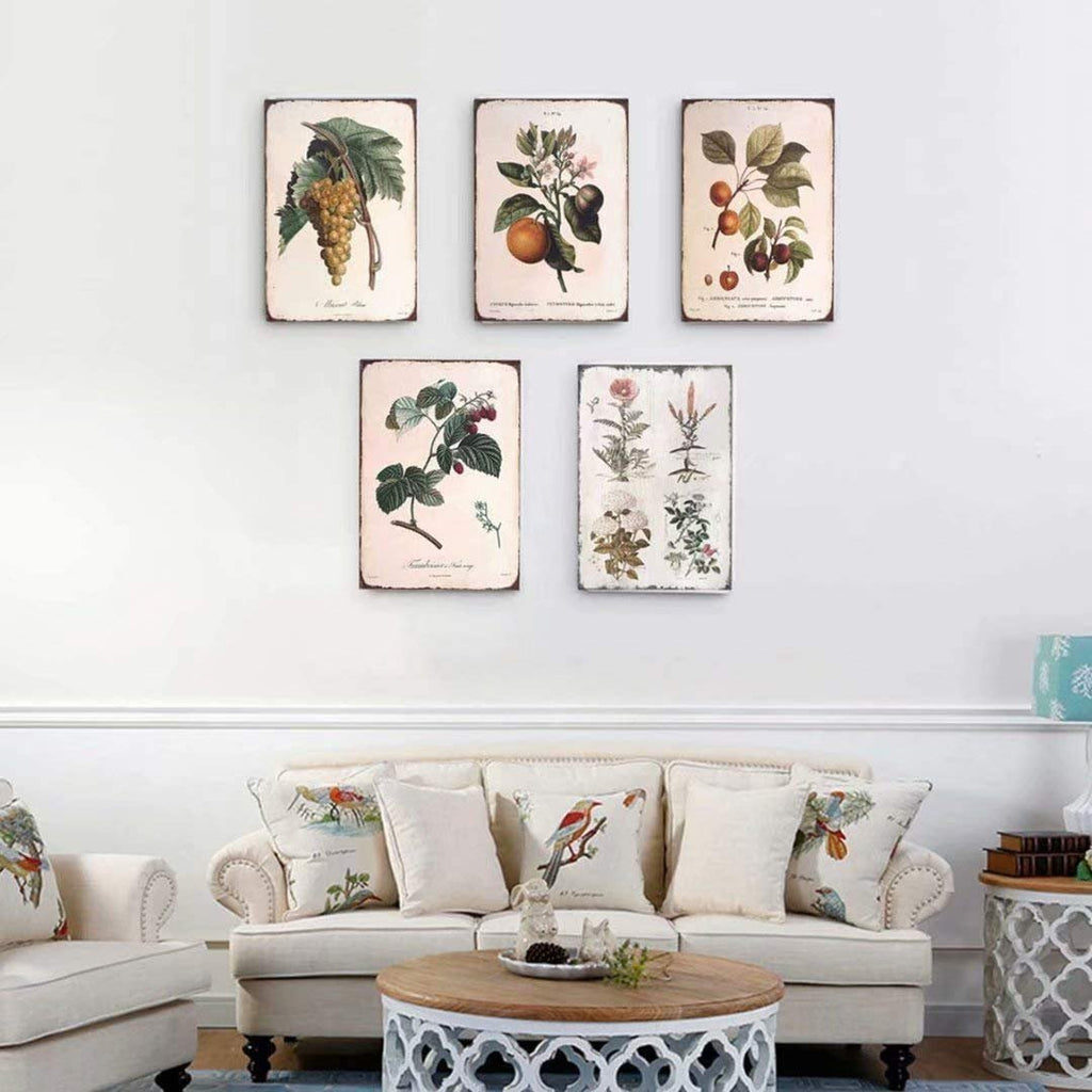 Five vintage botanical art tin signs hanging on a wall above a sofa with decorative pillows.