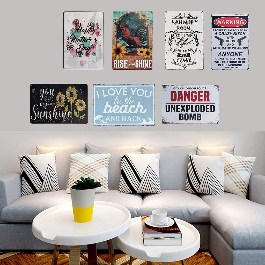 Collection of eight decorative metal tin signs displayed on a wall above a sofa, featuring various sayings and graphics.
