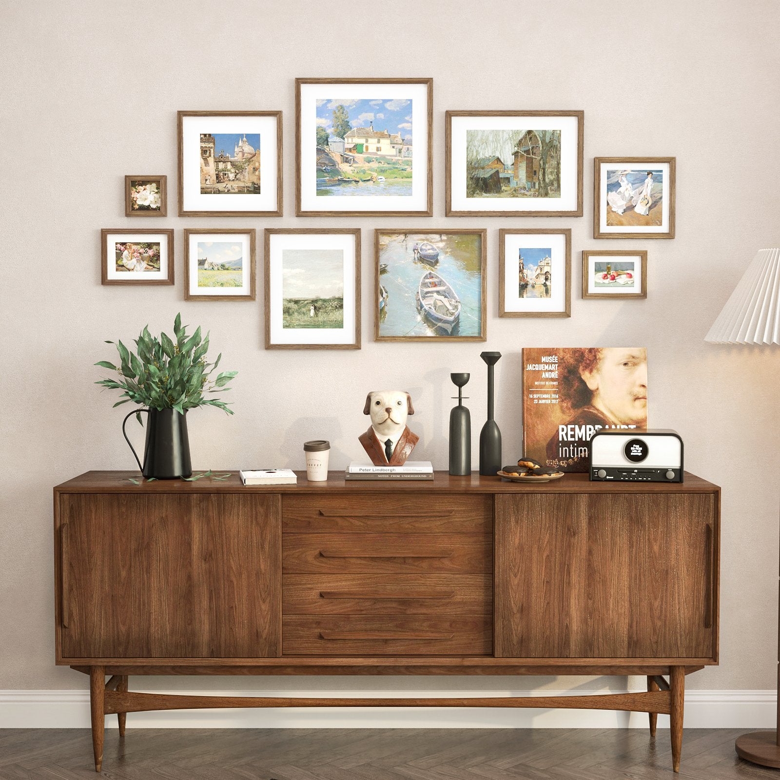 Gallery wall of eight framed landscape and portrait paintings above a wooden credenza with decorative items.