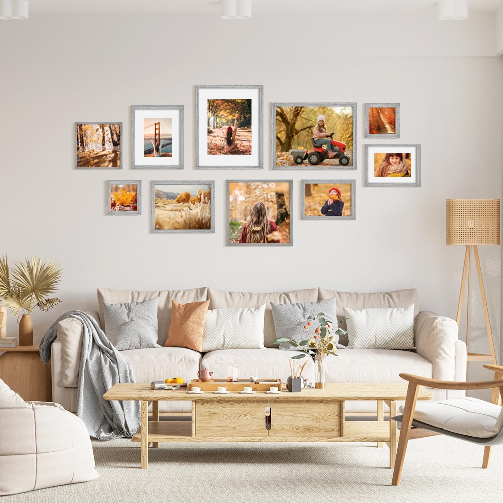 Gallery wall of nine grey wood picture frames displaying autumn-themed photos above a sofa and coffee table.