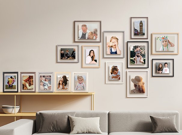 Gallery wall display of multiple picture frames with family photos on a neutral wall above a sofa.