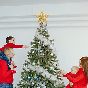 Family decorating a Christmas tree with a gold sequin star topper
