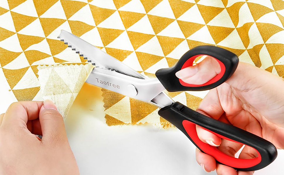 Pinking shears with zigzag teeth cutting fabric, held by hands with a patterned cloth in background.