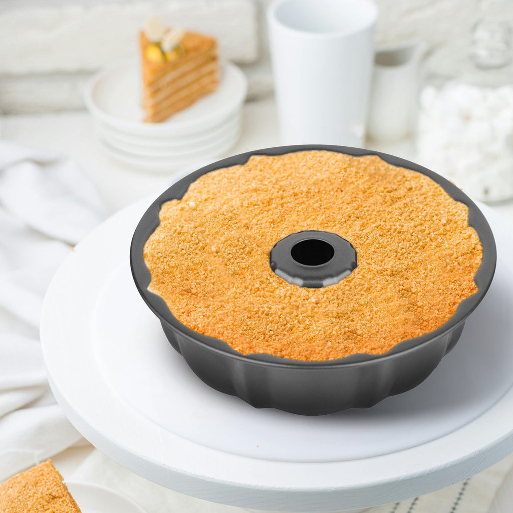 Fluted tube cake pan filled with crumb topping, presented on a white cake stand with a slice of cake in the background.