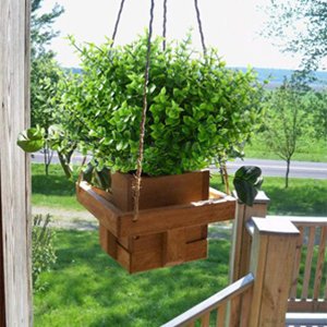 Hanging artificial boxwood greenery in a wooden planter basket on an outdoor porch.