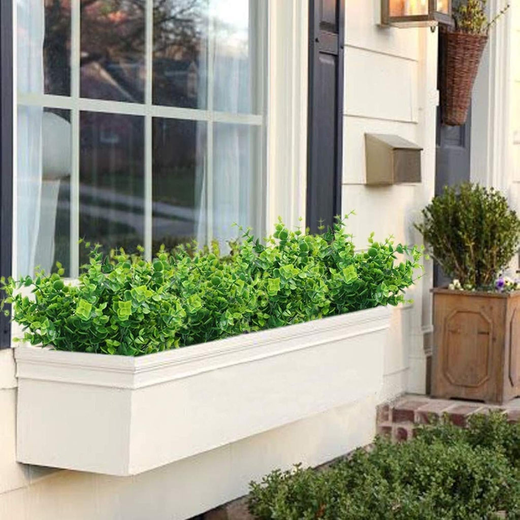 Artificial boxwood greenery in a white window planter box outside a house