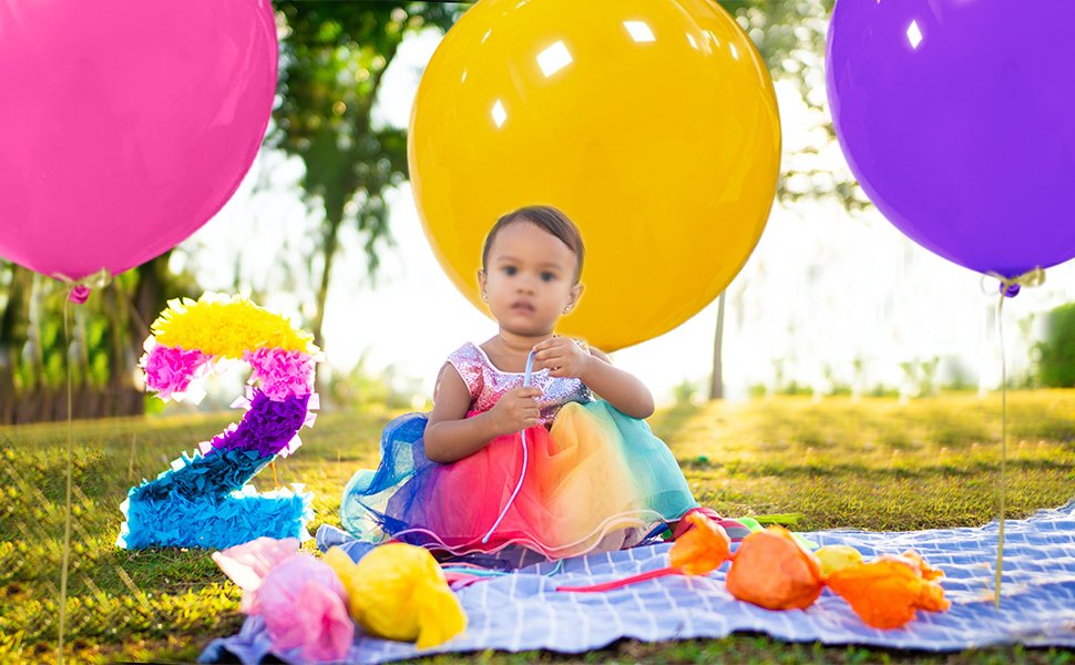 Baby girl sitting on a blanket with large balloons and a number 2 decoration