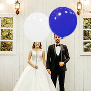 Bride and groom holding large white and blue balloons at an outdoor wedding ceremony