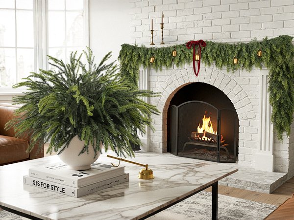 Artificial green cedar garland draped over a white brick fireplace with a fire burning inside.