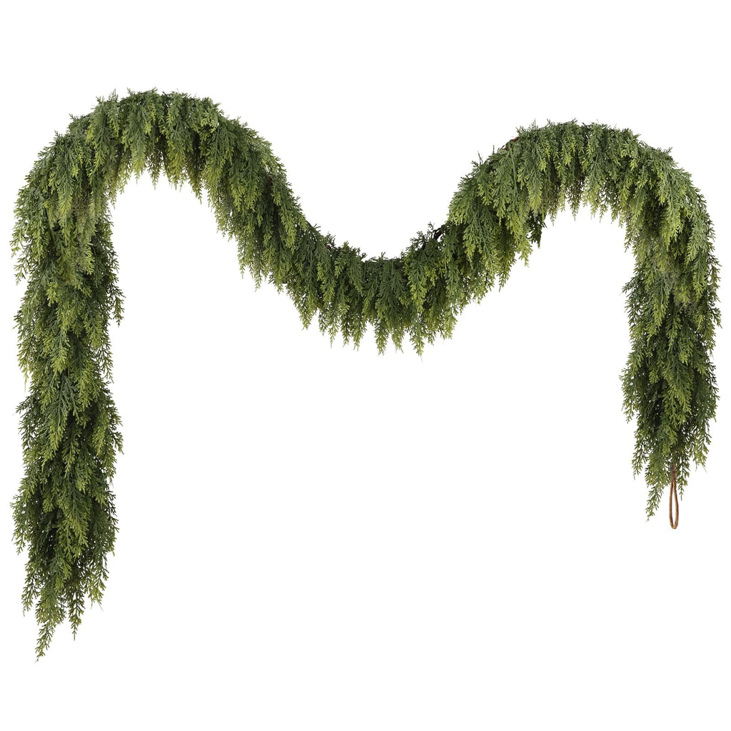 Artificial green cedar garland draped in a curve against a white background, showing realistic foliage and a loop at one end.