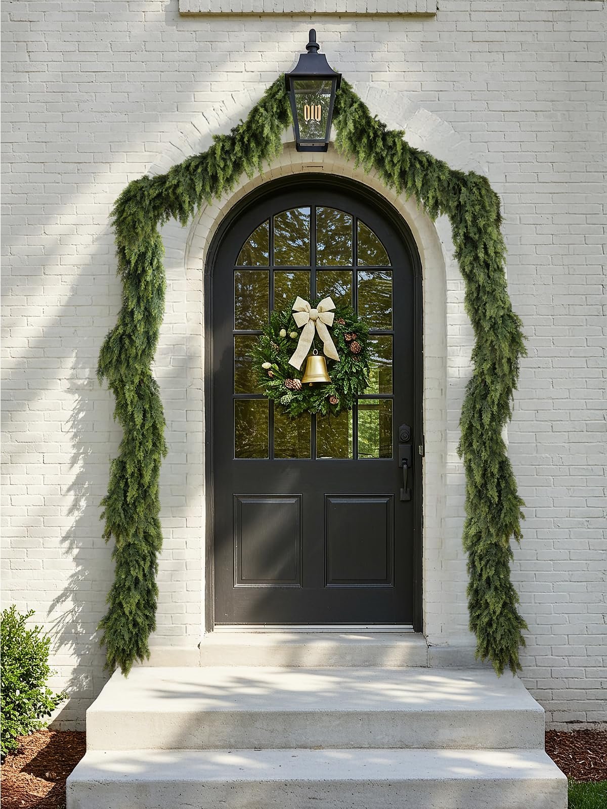 Green cedar garland draped over an arched doorway with a wreath on the door