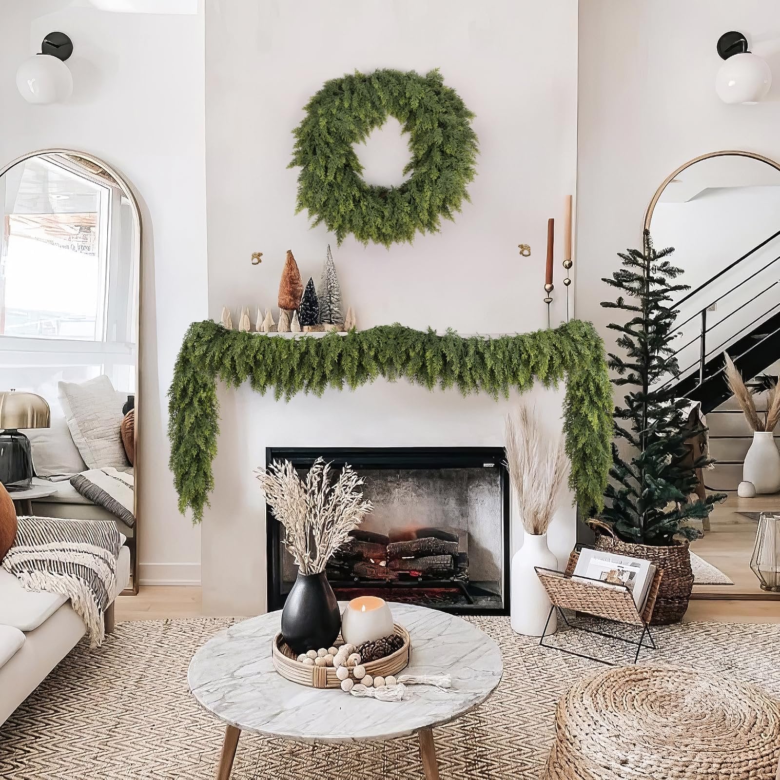 Christmas garland and wreath decorating a fireplace mantel with a small tree and decorative items