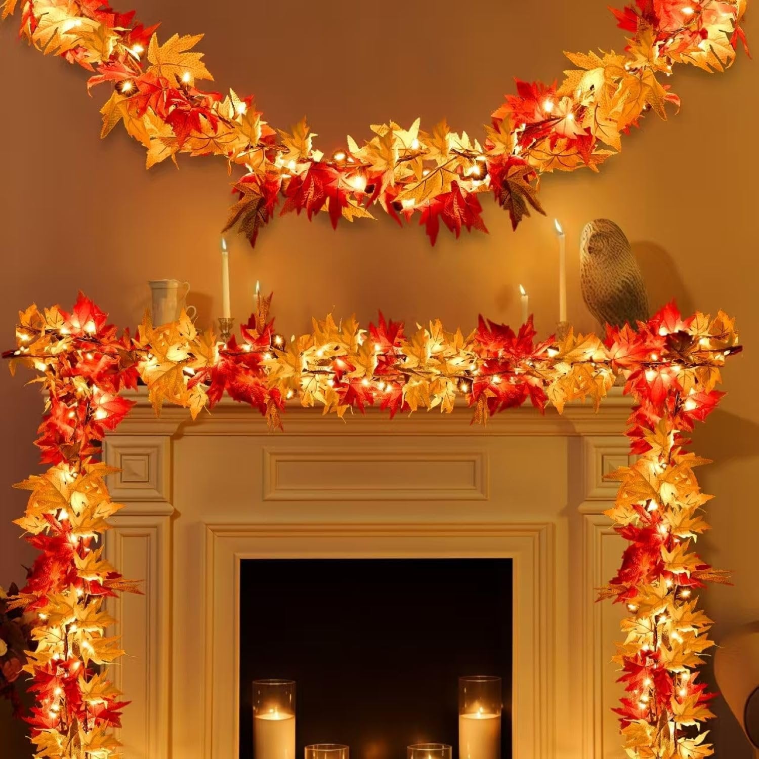 Fall maple leaf garland with warm orange lights draped over a fireplace mantel and wall