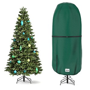 Decorated artificial Christmas tree next to a green upright Christmas tree storage cover on a white background.