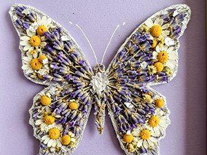 Butterfly craft made from dried flowers and lavender on a purple background