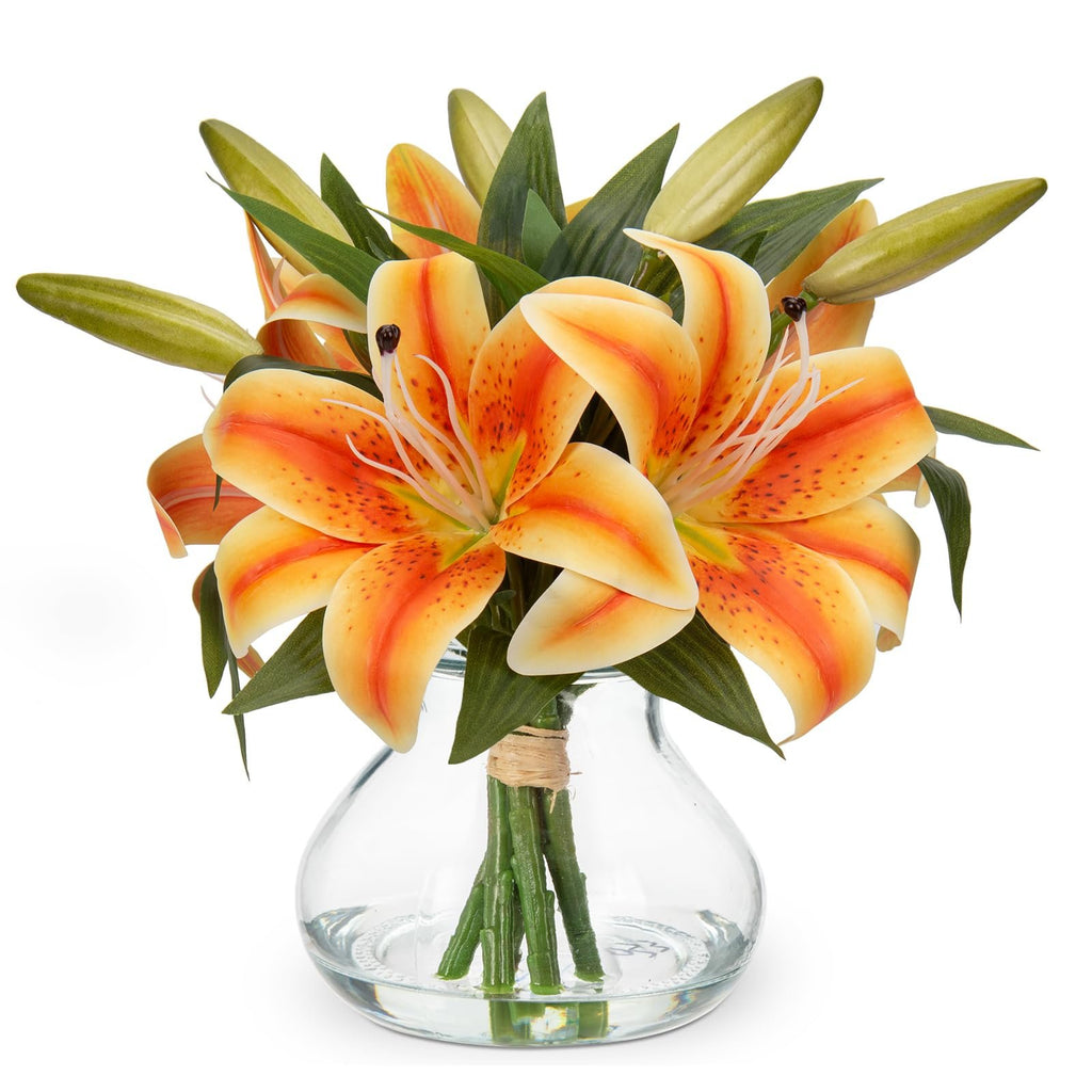 Orange tiger lily artificial flower arrangement with six silk heads in a clear glass vase with faux water, isolated on white.