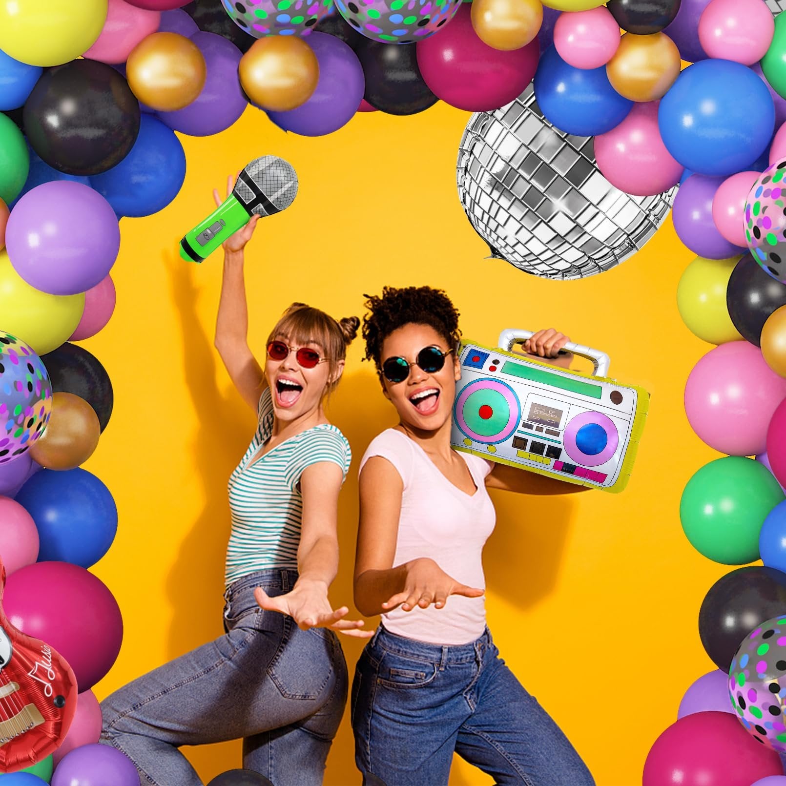 Two women dancing with retro party props and balloons, one holding a microphone, the other a boombox.