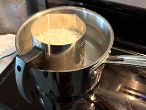 Soy candle making kit wax melting in a double boiler on a stovetop.