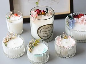 Five decorative soy candles with dried flowers and herbs, one large candle has a label that reads 'Pure Soy Candle'.