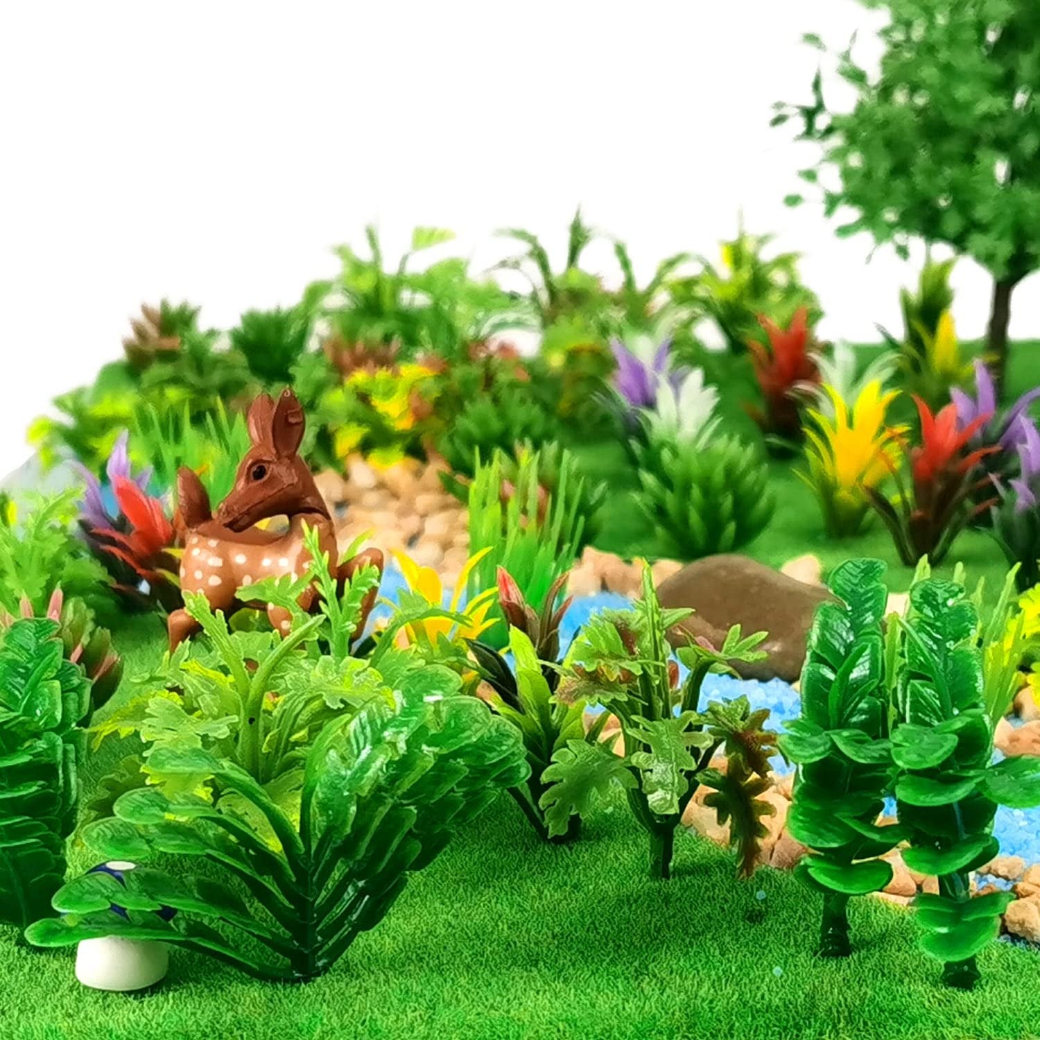 Miniature model trees and plants with a deer figurine in a diorama setting.