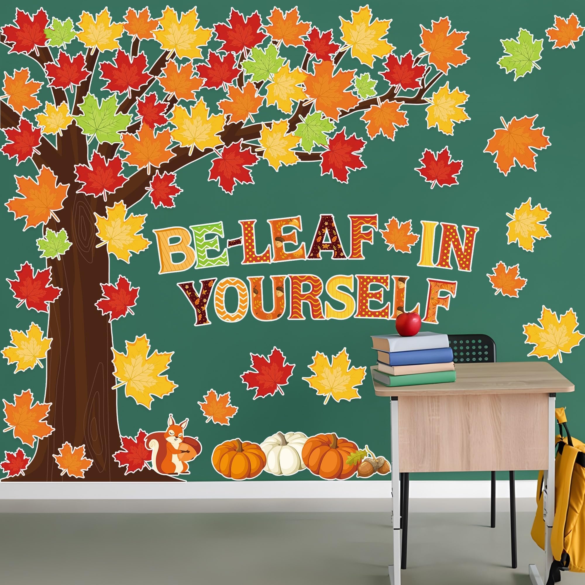 Fall bulletin board display with a tree, colorful maple leaves, pumpkins, acorns, and the phrase "BE-LEAF IN YOURSELF" on a green background.